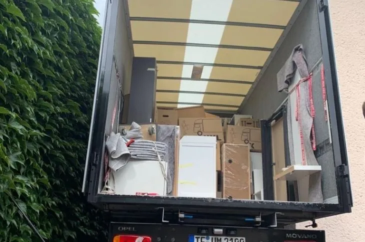 umzugshelfer steht vor umzugswagen der umzugsfirma